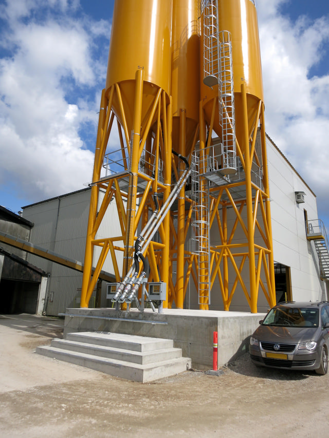 2 orange cementsiloer udenfor fabriksbygning.